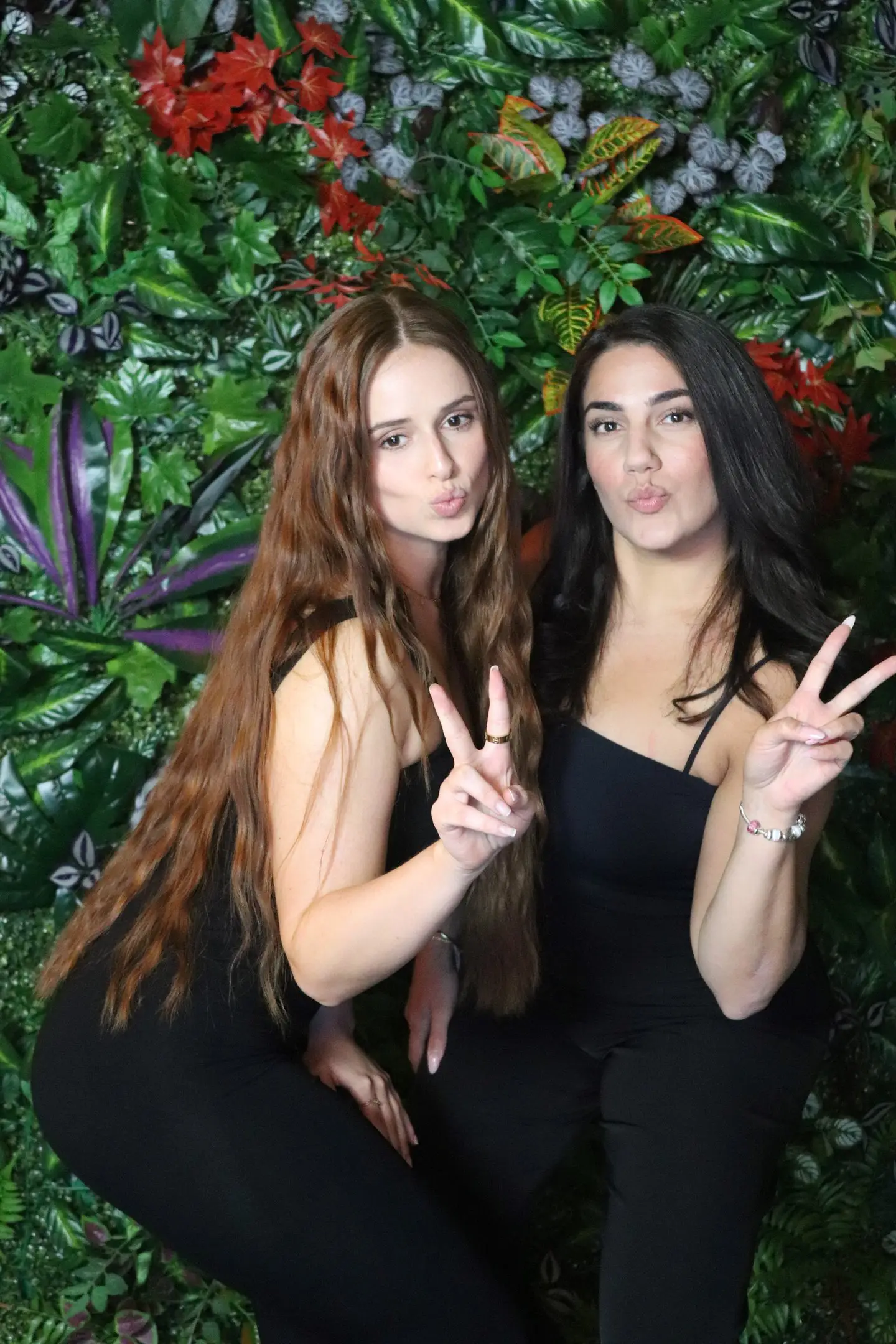 Zwei junge Frauen posieren vor einer grünen Pflanzenwand für die Fotobox in Pforzheim