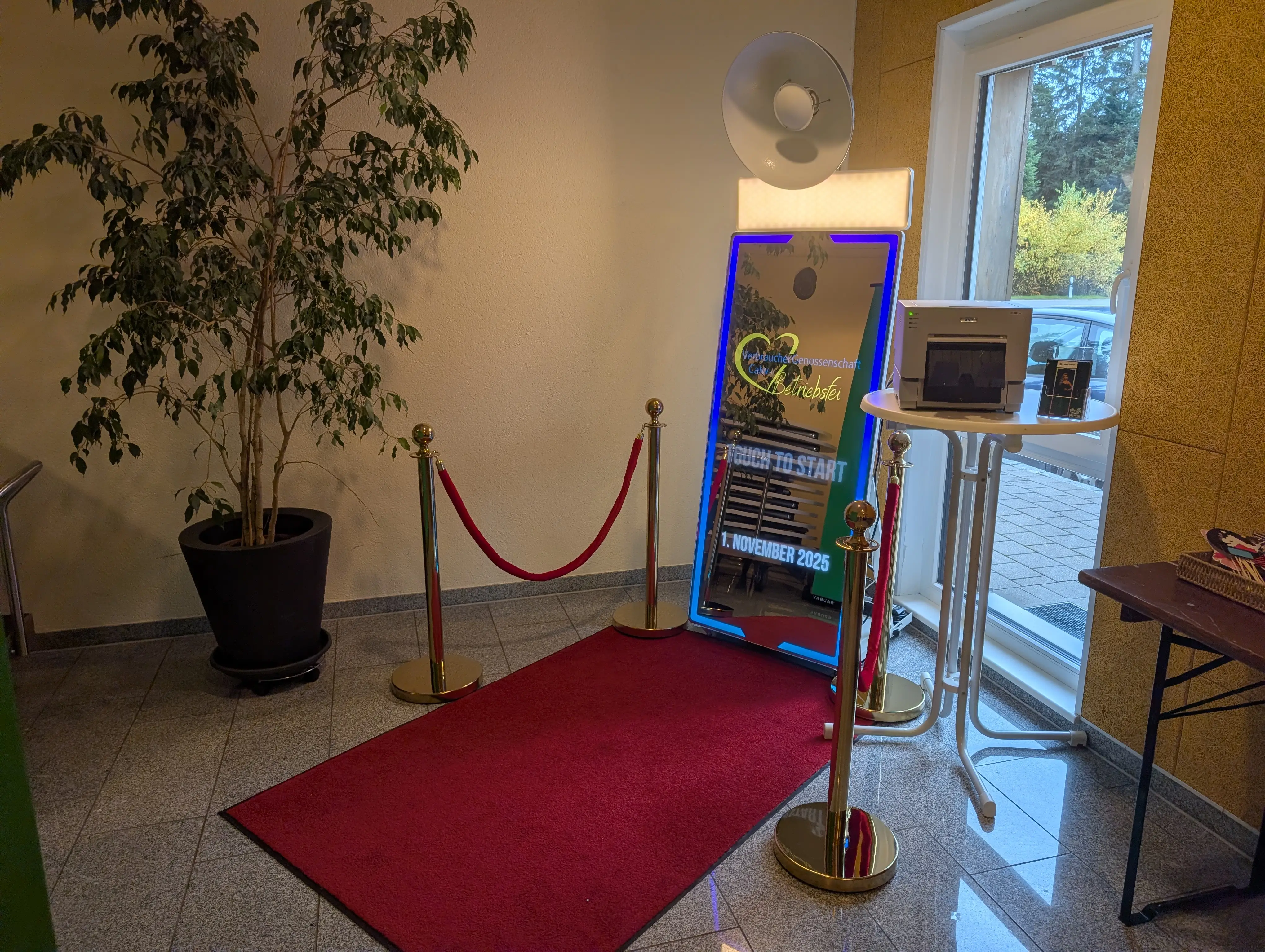 Premium Spiegel Fotobox aufgebaut für eine Unternehmensfeier mit rotem Teppich und goldenem Personenleitsystem