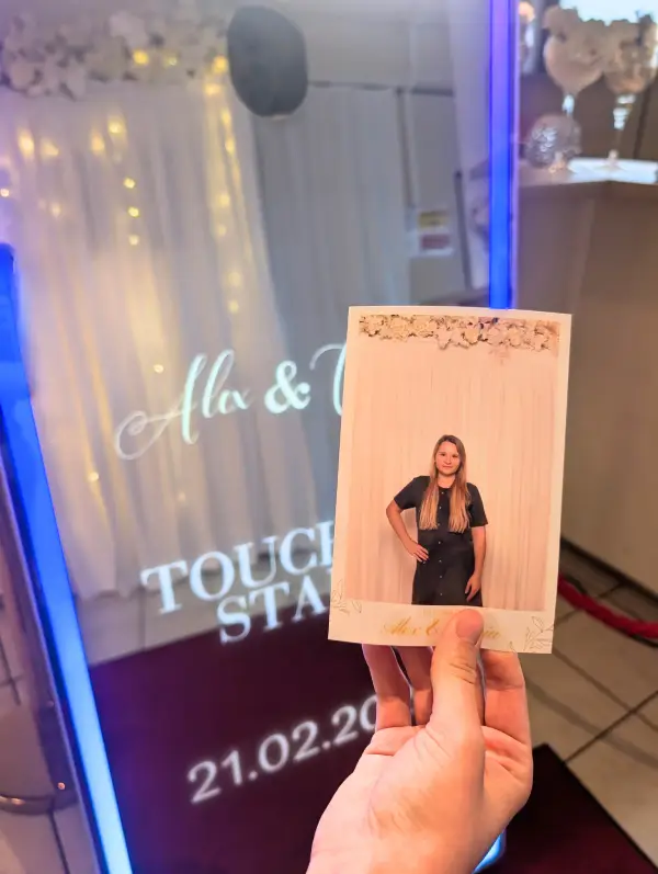 Hand hält Sofortdruck vor dem Fotospiegel, Ergebnis einer Fotobox-Buchung